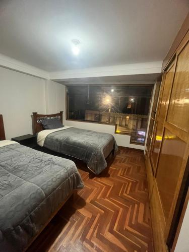 een slaapkamer met 2 bedden en een houten vloer bij Temporary departament in Cuzco