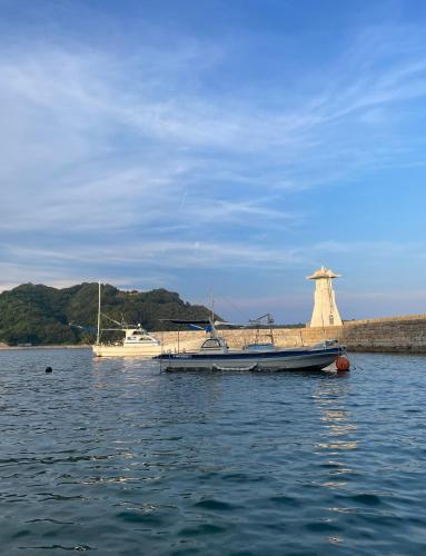 a boat in the water next to a lighthouse at 浪漫宿花町 in Mitarai