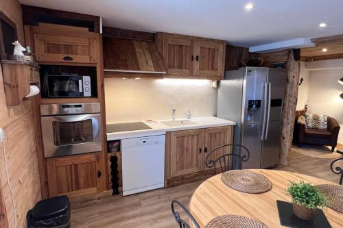 a kitchen with wooden cabinets and a table and a refrigerator at La Dorbluche apartment 4-6 person in Longefoy