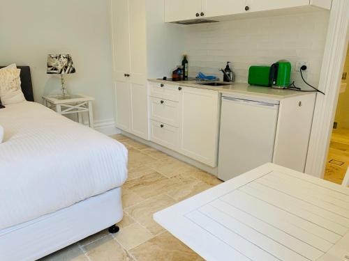 a white bedroom with a bed and a kitchen at Balmoral Salt in Sydney