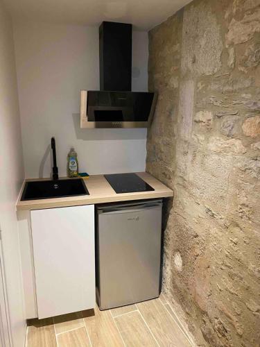 a small kitchen with a sink and a stone wall at Gramat studio de charme in Gramat