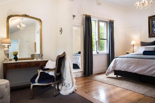 a bedroom with a bed and a mirror and a chair at Illoura in Hepburn Springs