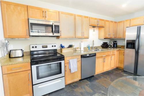 a kitchen with wooden cabinets and stainless steel appliances at Pineapple Paradise - Mission Beach - Stunning in San Diego