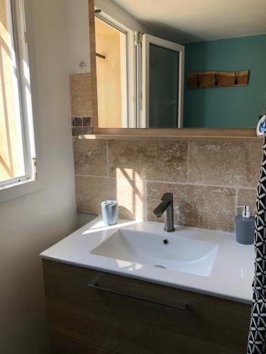 une salle de bain avec un lavabo blanc et un miroir dans l'établissement L'ensoleillade du Pont du Gard, à Vers-Pont-du-Gard