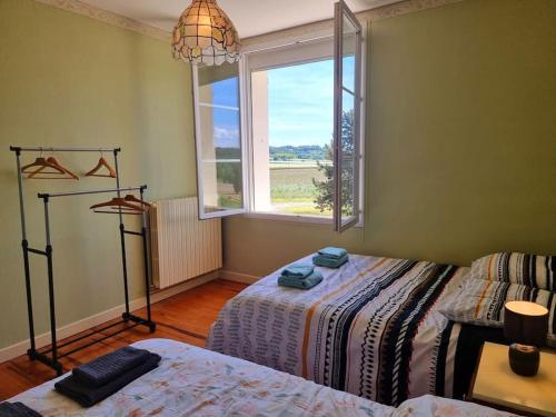 a room with two beds and a window at La maison d’Emilie in Margès