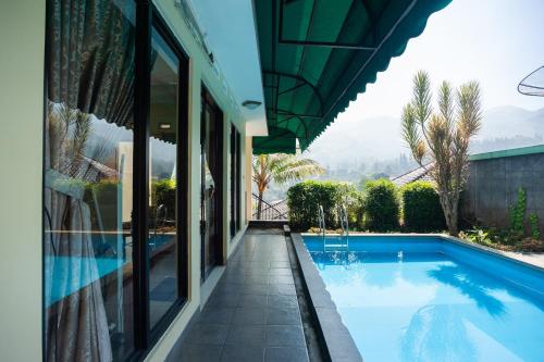 a swimming pool in a house with a view of the mountains at Urbanview Resort Syariah Khansa Cisarua Puncak by RedDoorz in Tagalbato