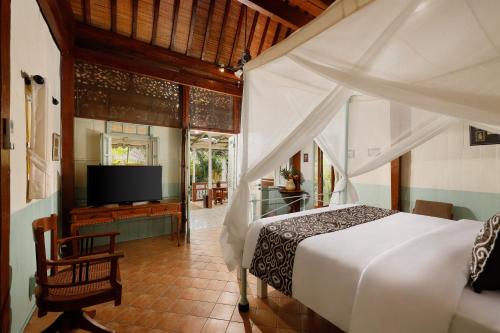 a bedroom with a white bed and a tv at Puri Tempo Doeloe Boutique Hotel in Sanur