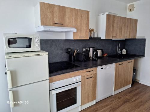 uma cozinha com electrodomésticos brancos e armários de madeira em Appartement Chez A.S.Y. em Guérande