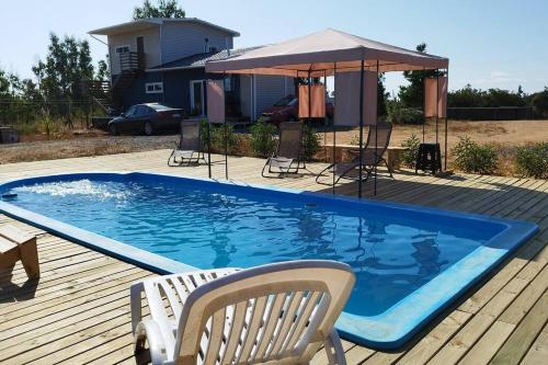 a swimming pool on a deck with chairs and an umbrella at Cabaña con fogon y tinaja en plena naturaleza! in Algarrobo