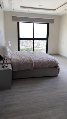 a bedroom with a bed and a large window at شقة خاصه مطله على الجبل in Al Baha