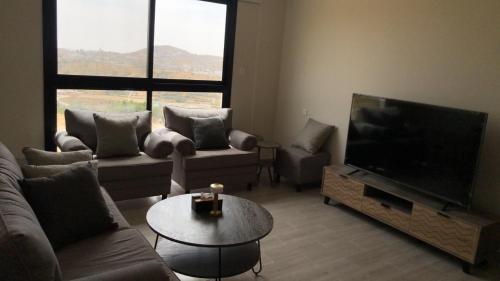 sala de estar con TV, sofá y mesa en شقة خاصه مطله على الجبل, en Al Bahah