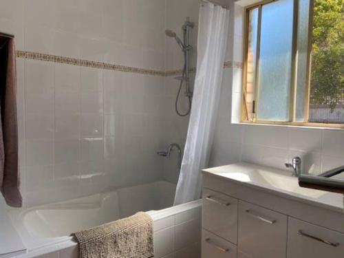 a bathroom with a tub and a sink and a window at Eos 2 in Esperance