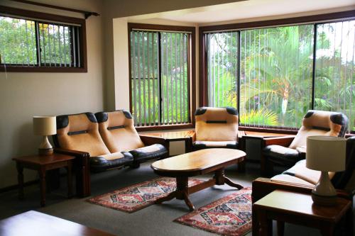 a living room with chairs and a table and windows at Bella Vista Bellingen in Bellingen