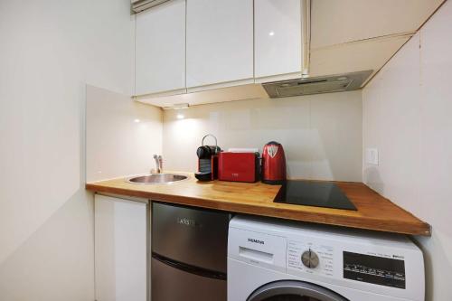 une petite cuisine avec un évier et une machine à laver dans l'établissement Cosy apartment - 1BR-3P - Arc de Triomphe, à Paris