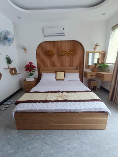 a bedroom with a large bed with a wooden headboard at Kami Hotel in Kinh Dinh