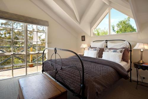 a bedroom with a bed and two windows at Lake Cottage in Daylesford