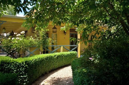 a yellow house with hedges in front of it at Lake Cottage in Daylesford