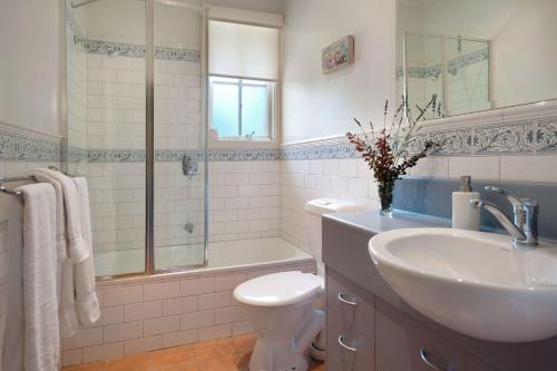 a bathroom with a sink and a toilet and a shower at Lake Cottage in Daylesford