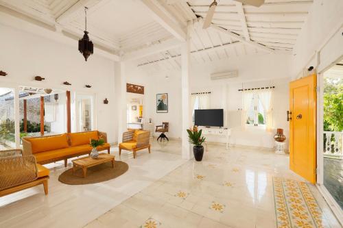 a living room with yellow furniture and a tv at Puri Tempo Doeloe Boutique Hotel in Sanur