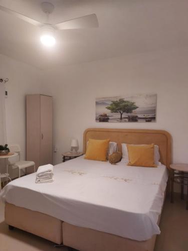 een slaapkamer met een groot wit bed met gele kussens bij המקום של כרמית in Neve Zohar