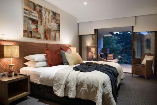 a bedroom with a large bed and a balcony at Lake Daylesford Lodge 5 in Daylesford