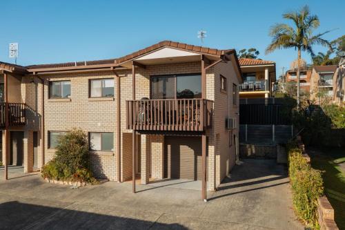 a large brick house with a balcony at Orana by Experience Jervis Bay in Vincentia