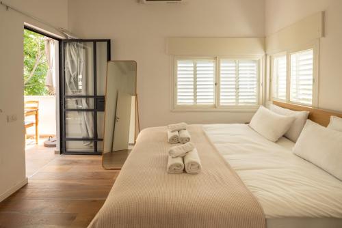 een slaapkamer met een groot wit bed en handdoeken bij Rustic Charm in Tel Aviv's Center by Sea N' Rent in Tel Aviv