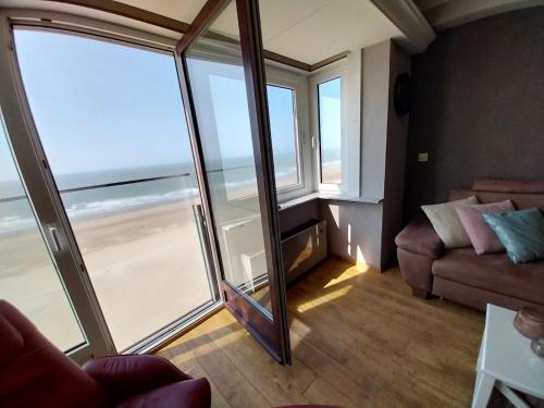 a living room with a couch and a large window at Lovely n° 9 op ieder moment een prachtig zeezicht & zwembad in Middelkerke