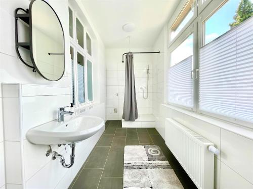 ein weißes Badezimmer mit einem Waschbecken und einem Spiegel in der Unterkunft Betongold in Duisburg