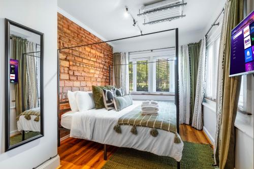 a bedroom with a white bed and a brick wall at Modern Century Loft At The Pillars in Cleveland
