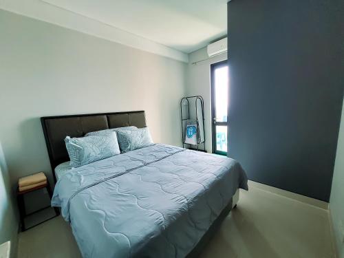 a bedroom with a bed with blue sheets and a window at Palam Mansion at Apartment One Residence in Batam Center