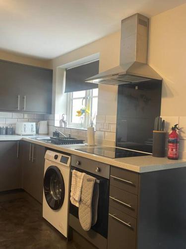 a kitchen with a stove and a washing machine at Fern House by Shortstays4u A Beautiful 2bedroom Townhouse with free parking in the town! in King's Lynn