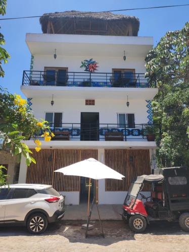 サン・フランシスコにあるDownTown Rooms San Pancho Mexicoの白い建物(ゴルフカート、傘付)