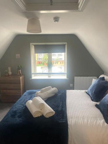 a bedroom with two towels on a bed with a window at Fern House by Shortstays4u A Beautiful 2bedroom Townhouse with free parking in the town! in King's Lynn