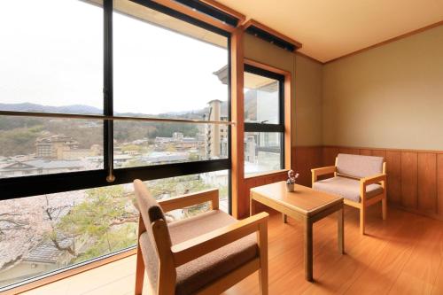 Habitación con silla, mesa y ventanas en 日長庵 桂月 en Hirugami
