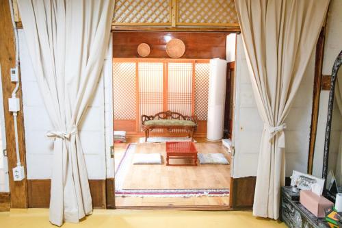 uma porta aberta para uma sala de estar com um sofá em Dongmyo Hanok Sihwadang - Private Korean Style House in the City Center with a Beautiful Garden em Seul