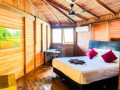 a bedroom with a bed with pink pillows and a desk at Villa Russerangan Grand Opening in Praya