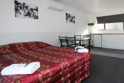 a hotel room with a red bed and a table at Brown Trout Motel in Pahiatua