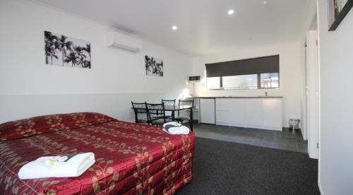 a hotel room with a red bed and a television at Brown Trout Motel in Pahiatua