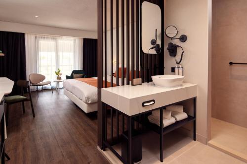 ein Bad mit einem Waschbecken und ein Bett in einem Zimmer in der Unterkunft Van der Valk Hotel Breukelen in Breukelen