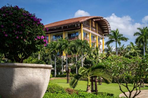 un edificio amarillo con palmeras delante en The St. Regis Sanya Yalong Bay Resort en Sanya