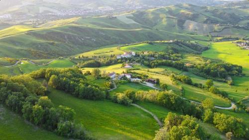 an aerial view of a green hillside with trees and houses at Locanda delle grotte di Onferno in Gemmano