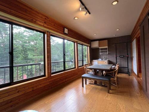 comedor con mesa y algunas ventanas en FOREST HOUSE en Kusatsu