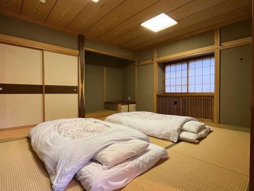 two beds in a large room with two windows at FOREST HOUSE in Kusatsu