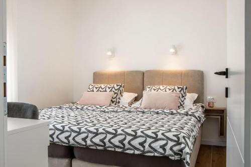 a bedroom with a large bed with a black and white comforter at Apartment Ladan in Trogir