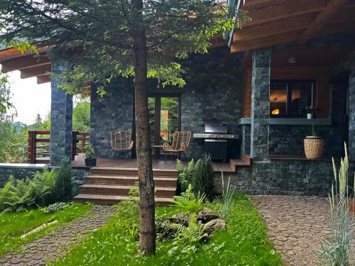 a stone house with a patio and a tree at Bazalt Wellness Villa in Harghita-Băi