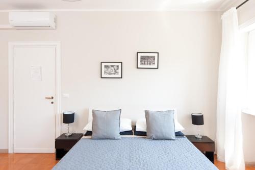 a white bedroom with a blue bed with blue pillows at La Lanterna Di San Pietro in Rome
