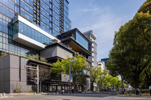 a tall building on a city street with trees at TIAD, Autograph Collection in Nagoya
