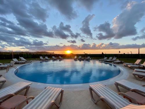 a swimming pool with lounge chairs and the sunset at Tarihi Kumbaba Otel in Sile