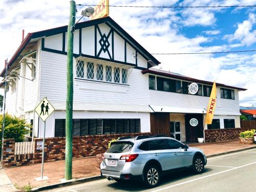 une voiture garée devant un bâtiment blanc dans l'établissement The Stanley Hotel Kilcoy, à Kilcoy